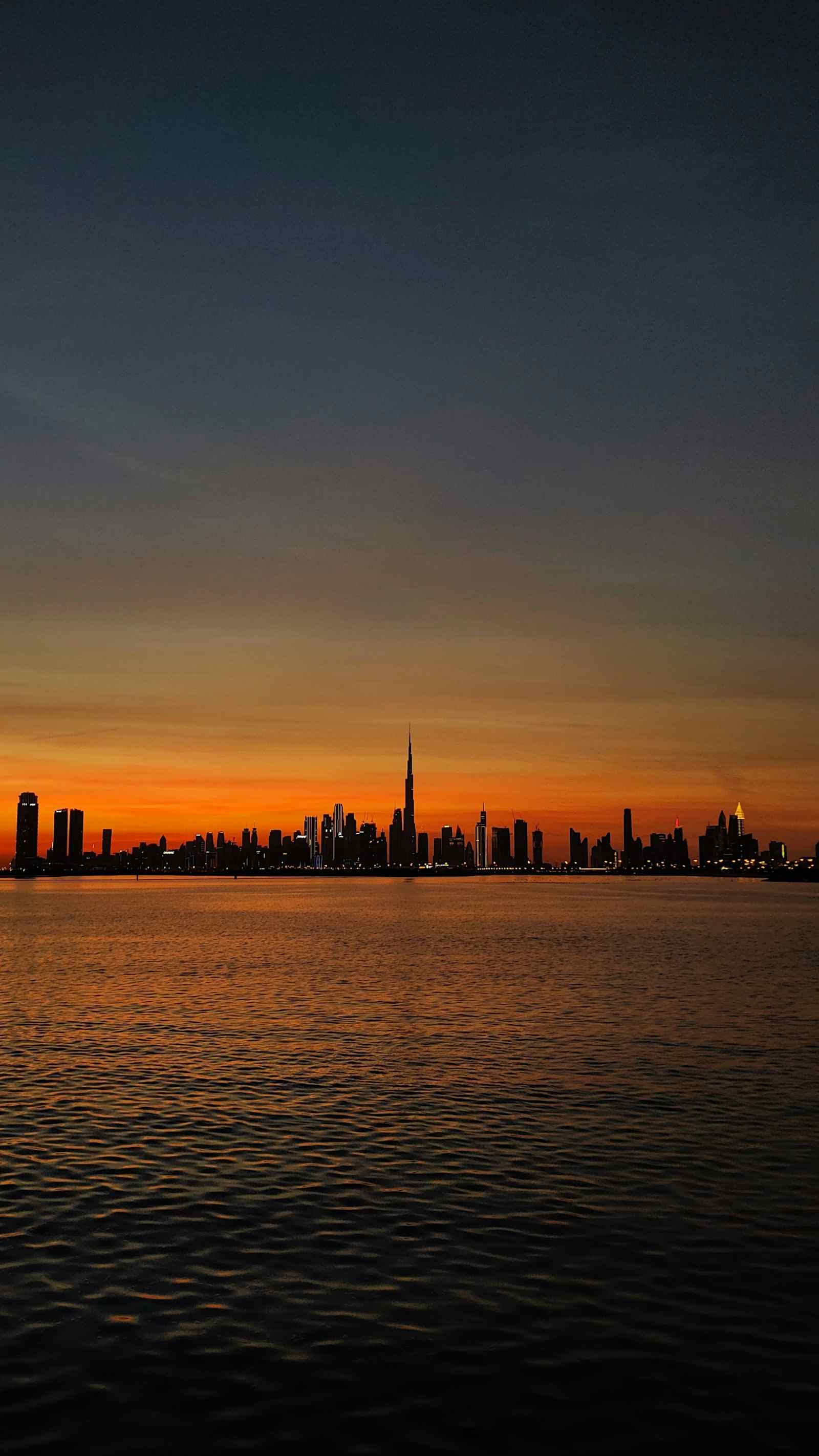 Dubai skyline across the water at dusk, a photograph by Asila